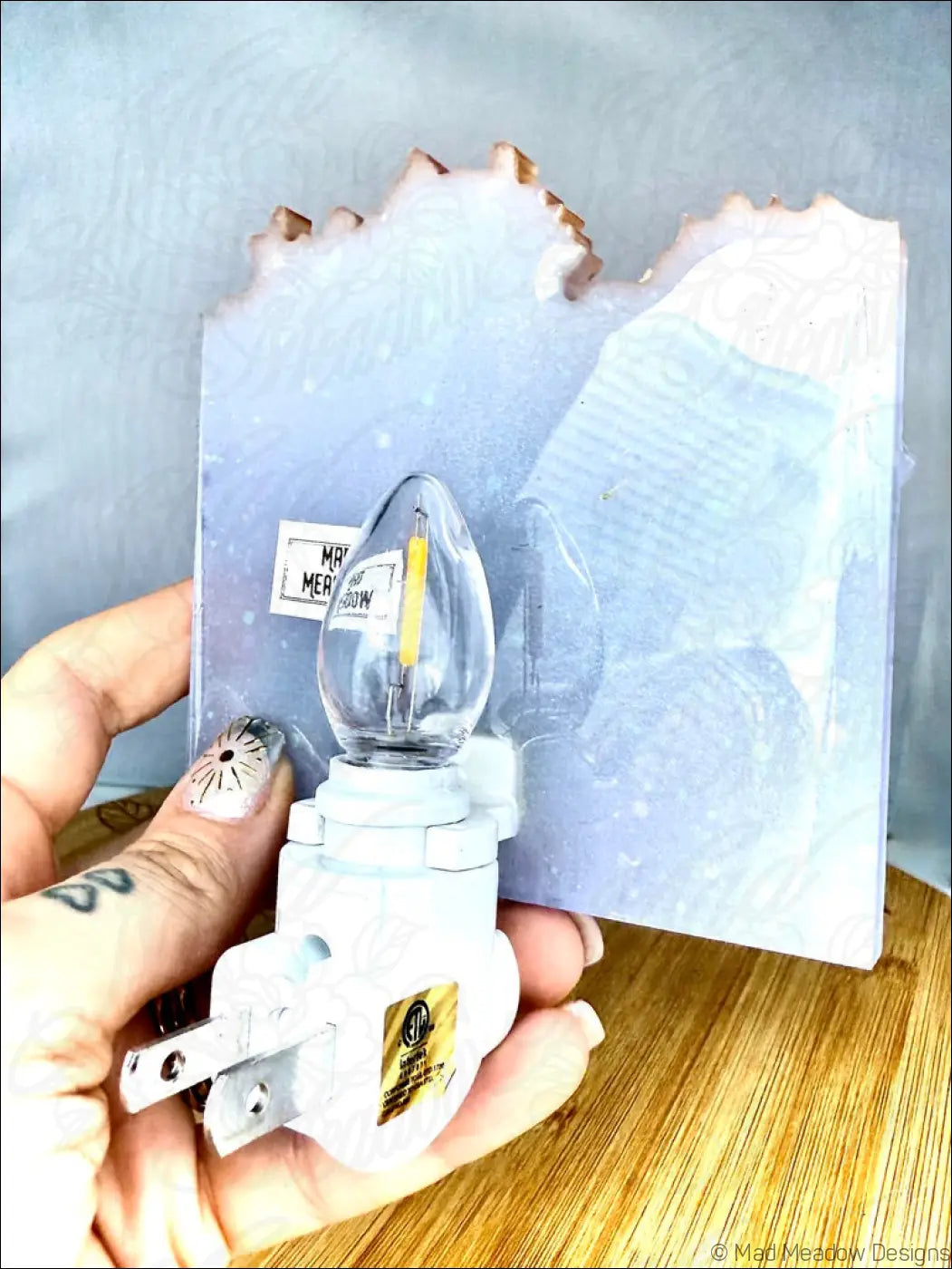 White plug-in wall night light with glowing purple and blue crystal cluster and frosted resin backing