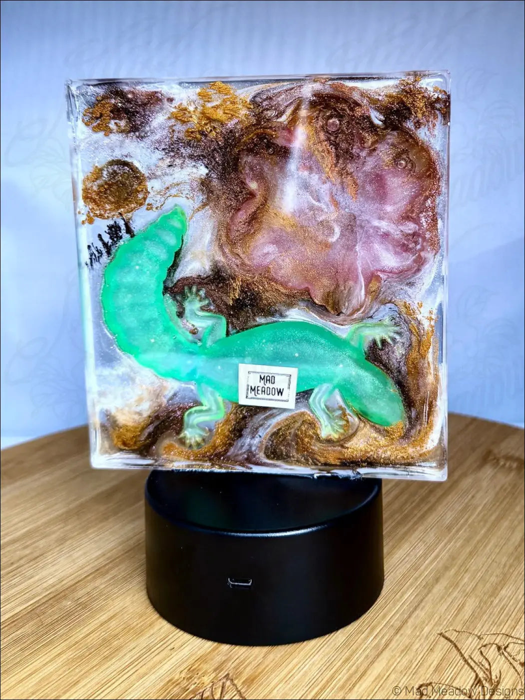 A translucent green salamander figurine in resin with shimmering gold accents on a black base for a pink lotus nightlight