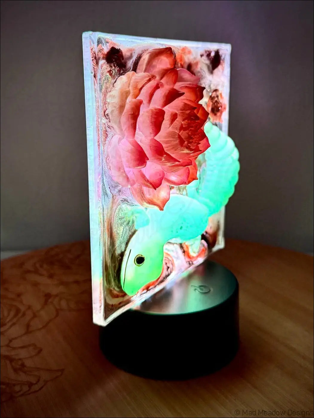 A translucent resin pink lotus nightlight with shimmering gold accents and an enchanting glowing gecko design in a rectangular frame