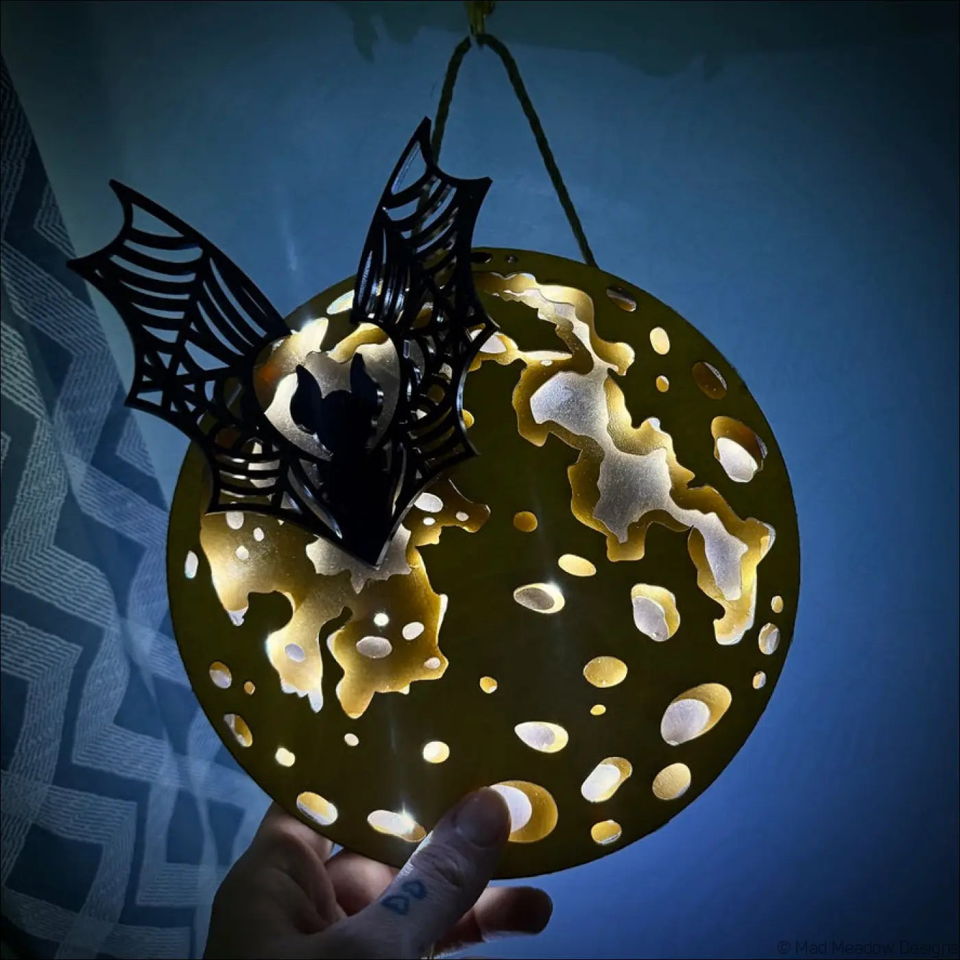 A black bat with webbed wings perches on a glowing golden moon led usb light with enchanting laser-cut wood details