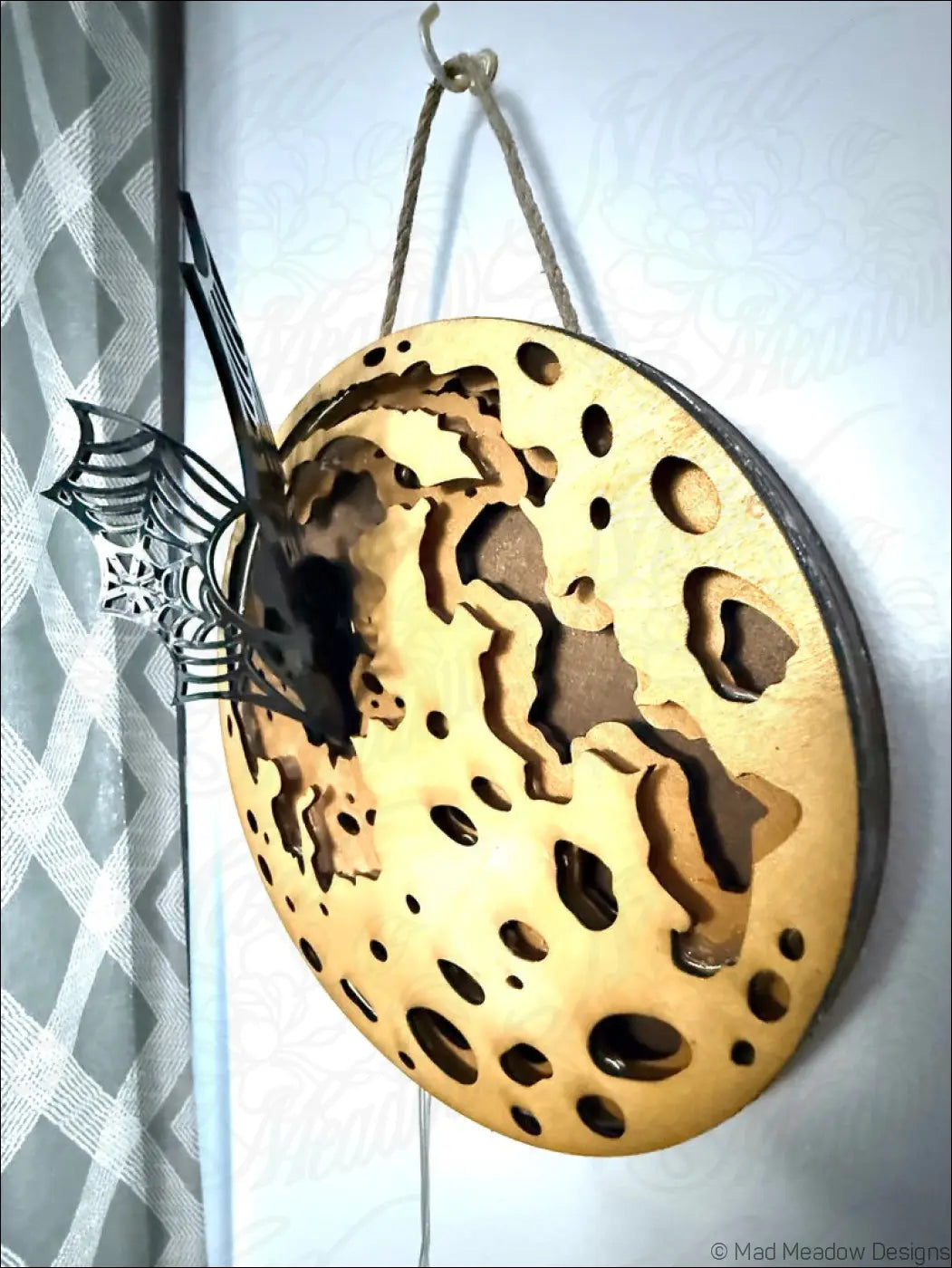 Glowing golden moon and bat hanging wall light with enchanting laser-cut wood and black metal fish design in light brown