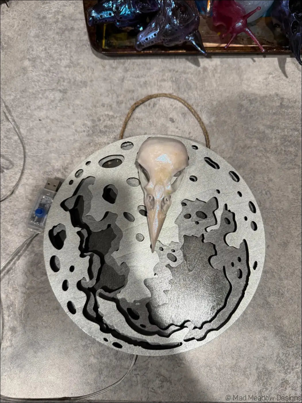 Glowing silver moon and raven skull hanging wall light with laser-cut moon wall and beige bird skull centerpiece