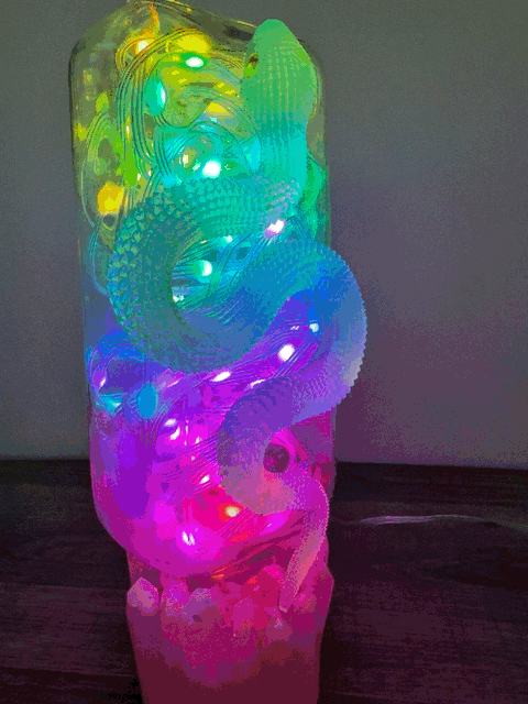 A translucent multi-colored led dragon figurine glowing inside on an antique glass apothecary bottle usb light