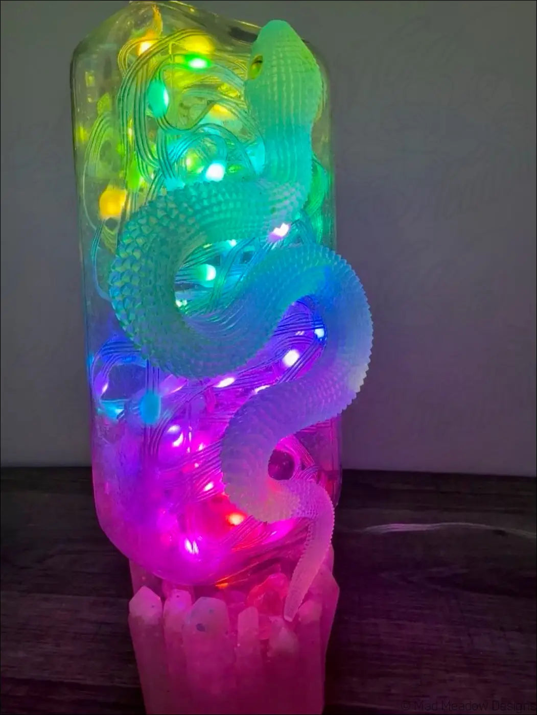 Glowing snake resin lamp with multi-colored translucent body and led lights on antique glass apothecary bottle base
