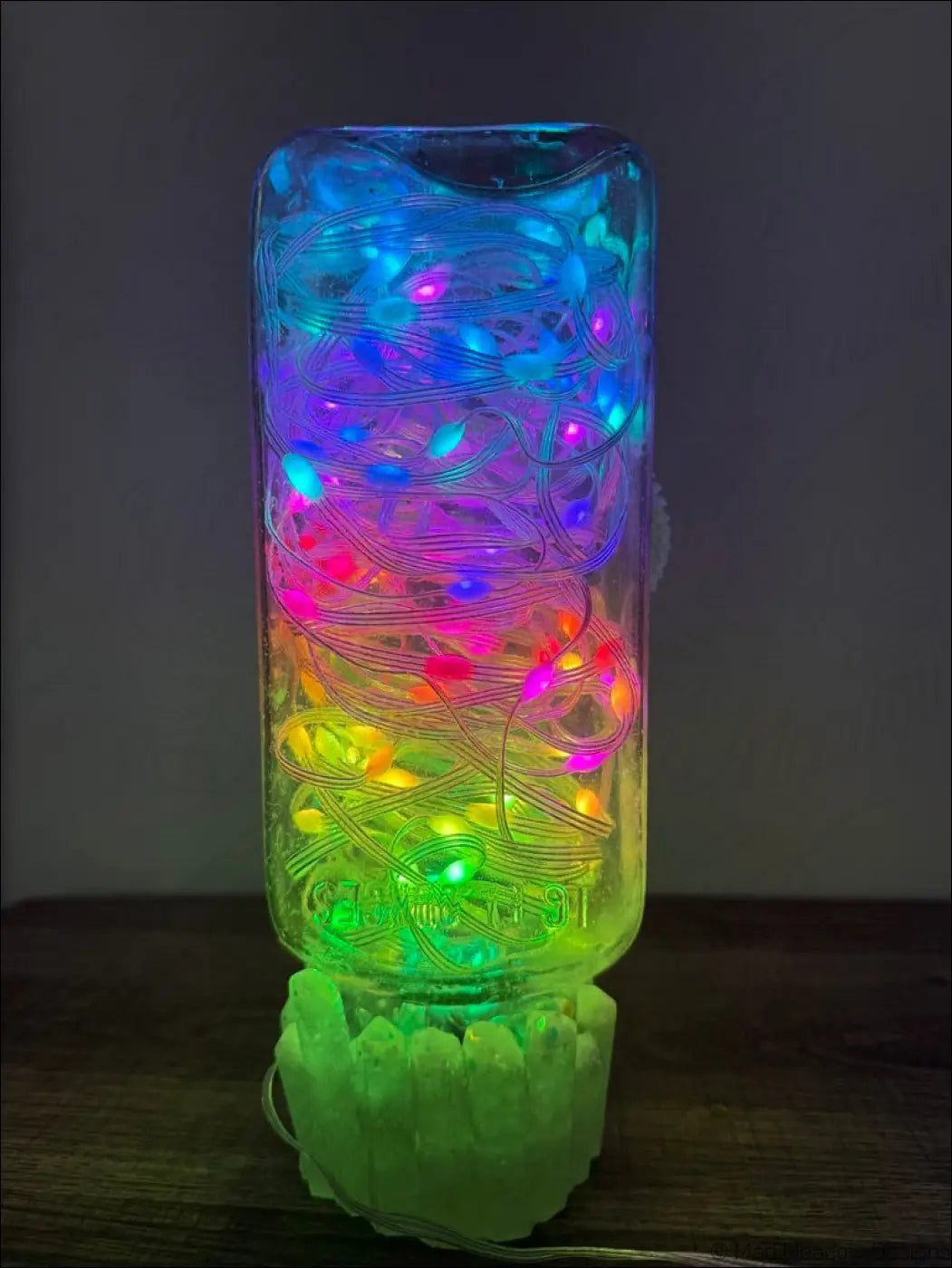A clear glass antique apothecary bottle with colorful glowing snake led string lights on a crystal dish usb light