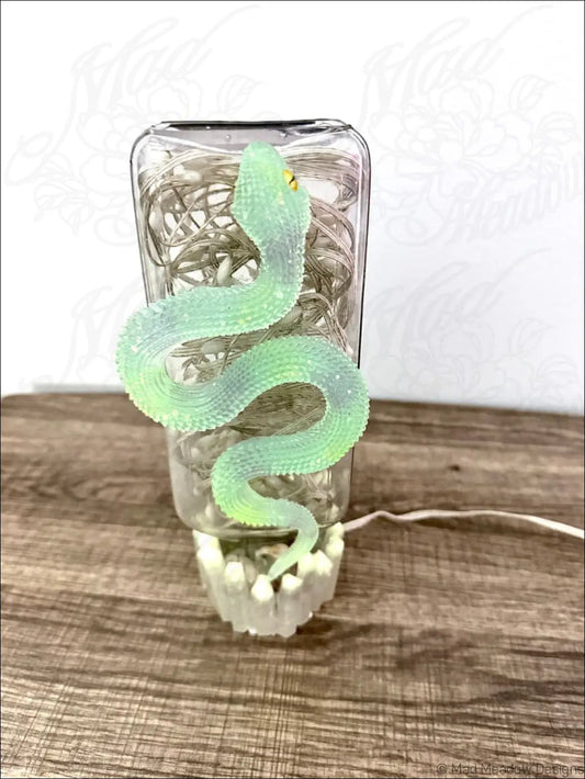 Glowing snake usb light with translucent green textured snake coiled on antique glass jar with string lights
