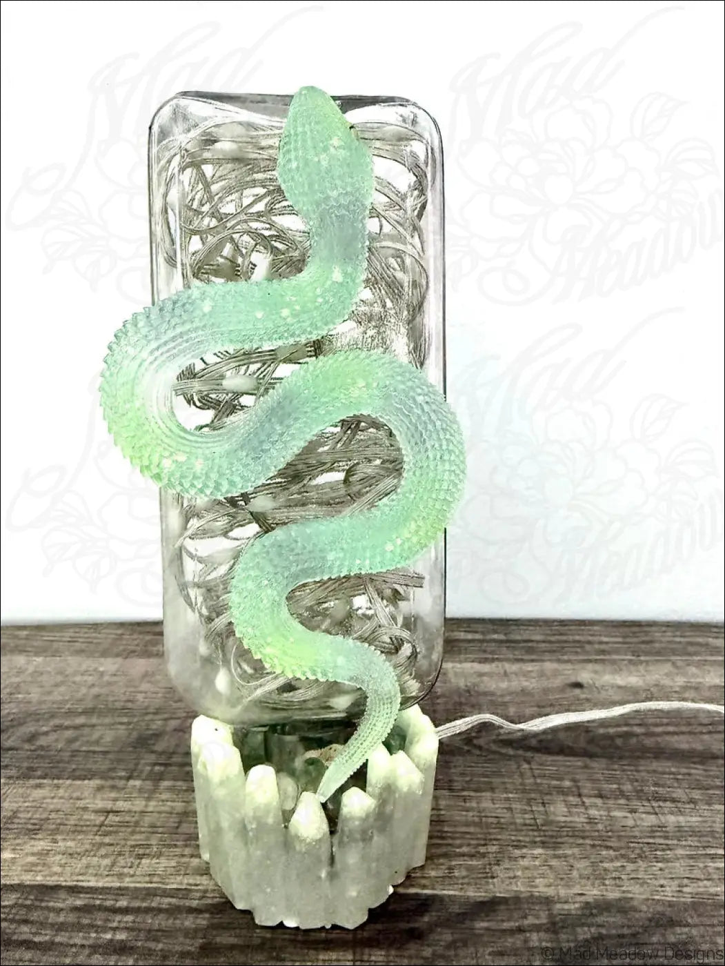 A translucent green snake-shaped lamp with textured scales coils around a glass jar apothecary bottle usb light