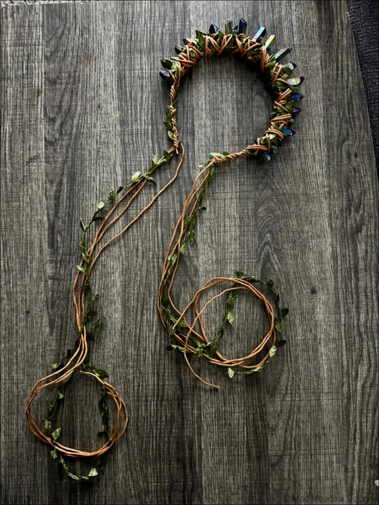 A handcrafted dark golden goddess headband crown with woven brown twine green leaves and iridescent blue-green crystals
