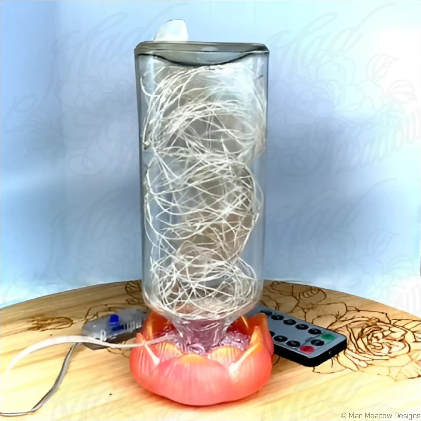 A clear glass antique glass apothecary bottle lamp with white led lights on a coral lotus flower base usb light