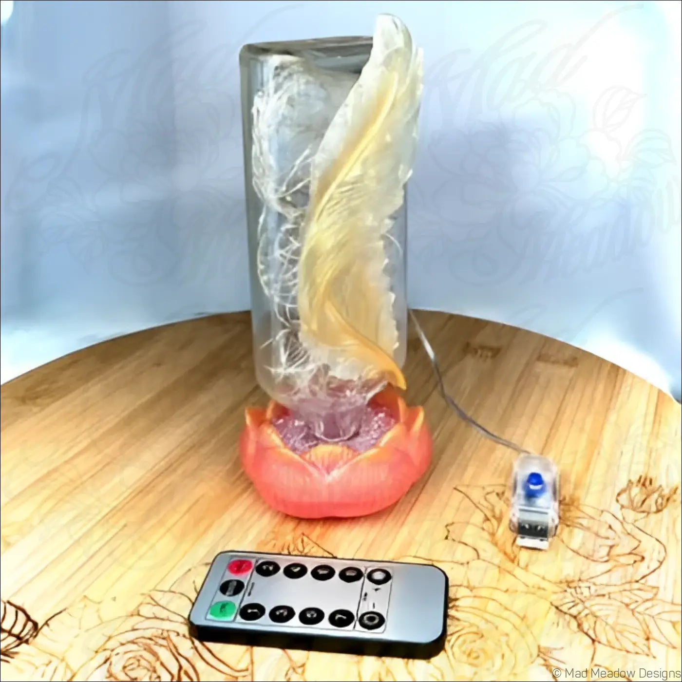 Golden feather usb light with translucent wing inside an antique glass apothecary bottle on red-orange lotus base