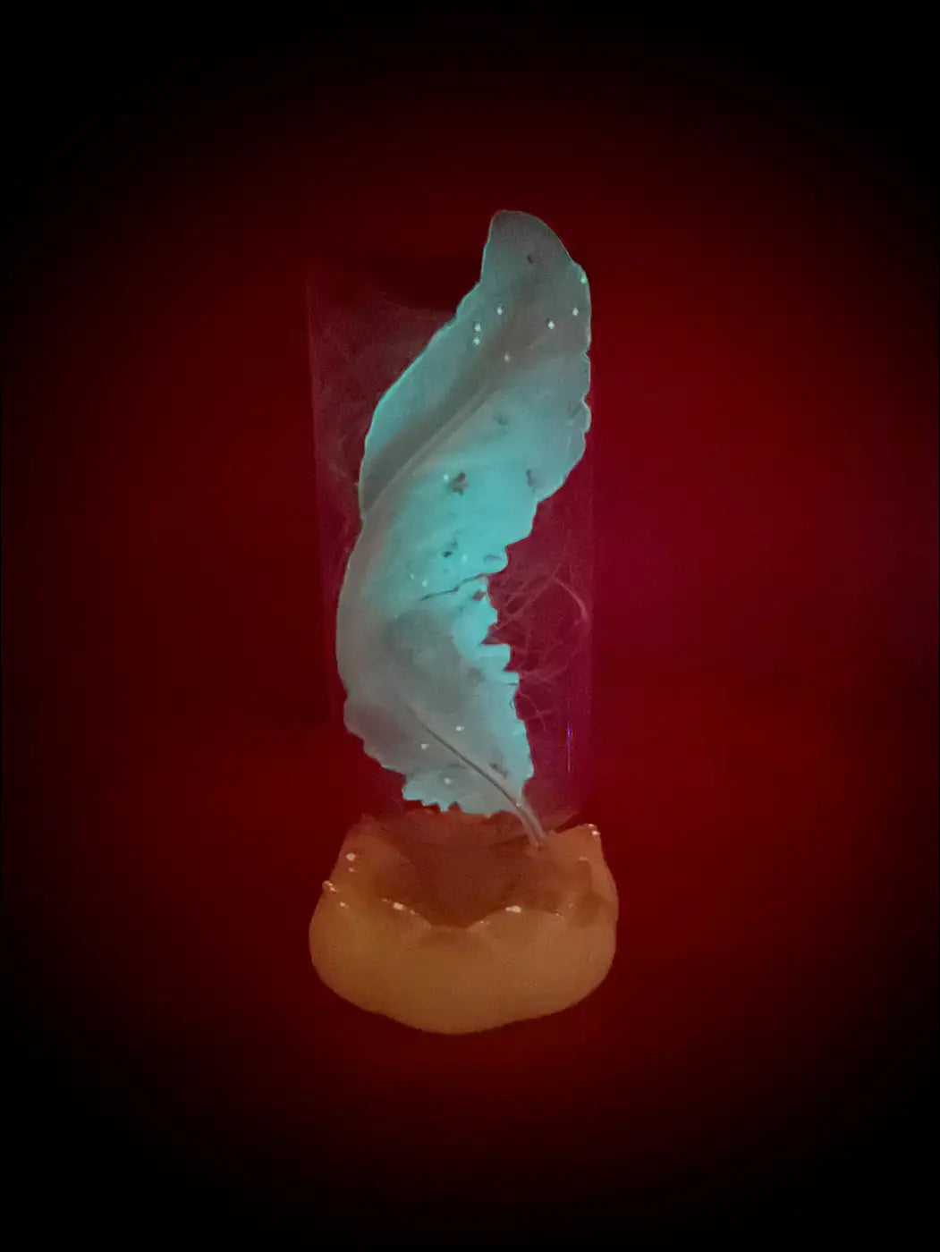 Translucent teal feather-shaped candle holder with glossy finish on amber base in antique glass apothecary bottle usb light