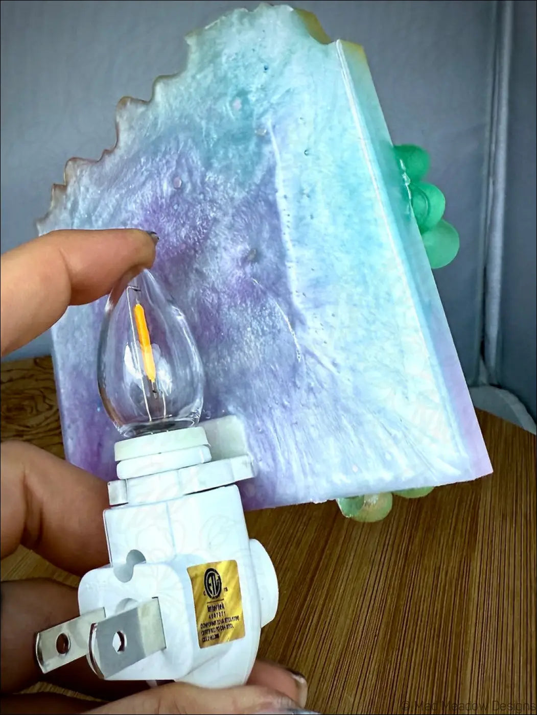 Translucent iridescent resin horned kitty cat garden wall night light with swirling purple and blue gradient on plug-in base