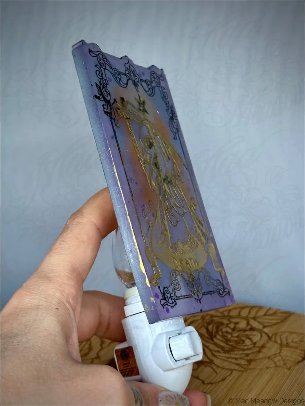 Pastel purple iridescent death tarot resin wall night light with gold crowned figure on plug-in base softly glowing