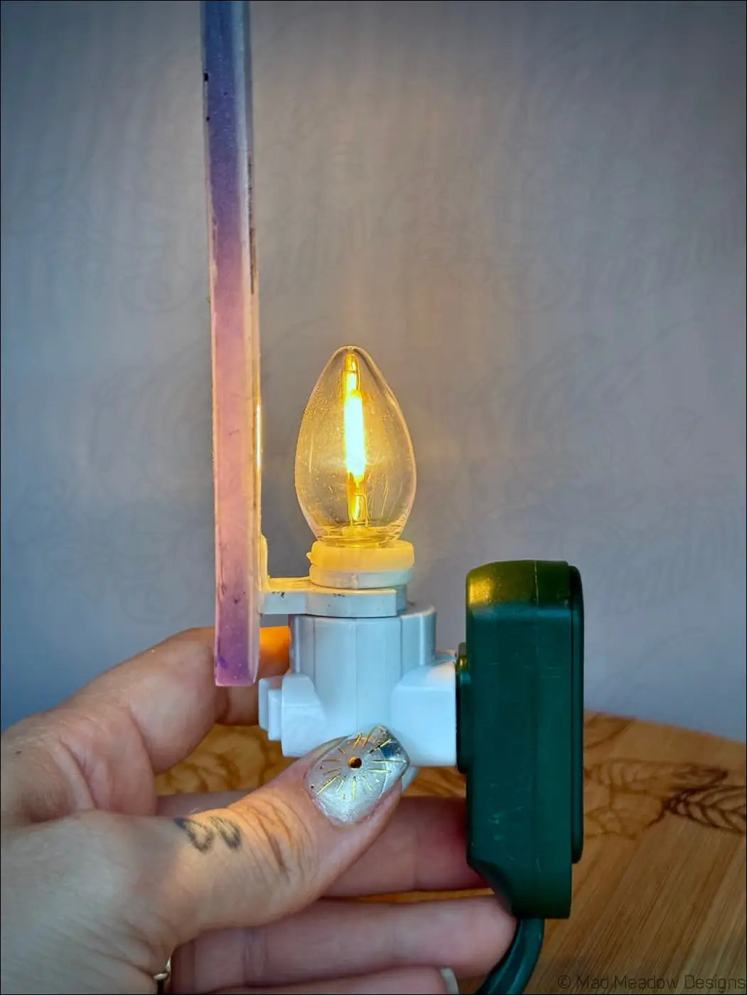 Iridescent death tarot wall night light with warm glowing teardrop led bulb on a white pastel purple plug-in base