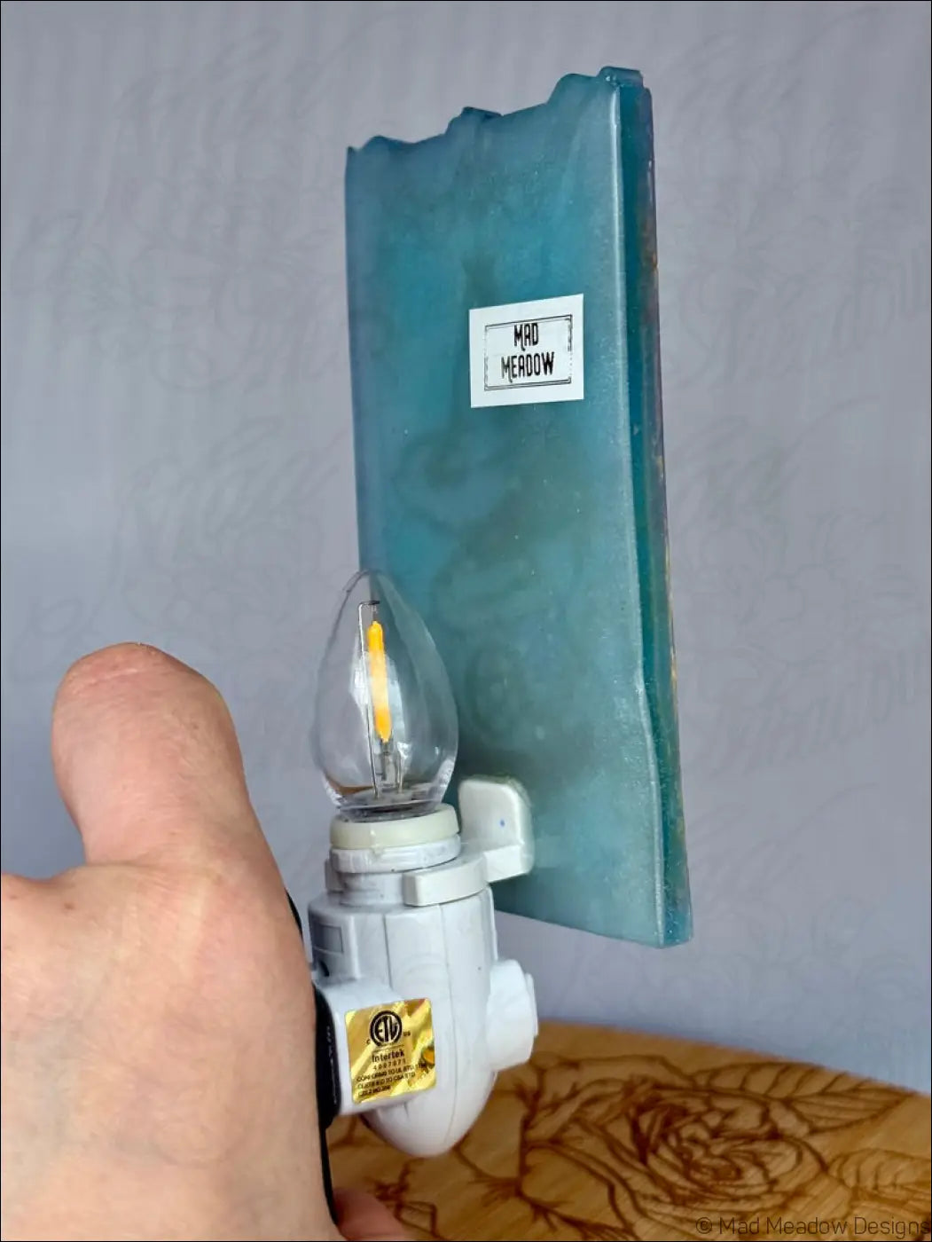 Teal blue resin wall night light with clear glass bulb and white base featuring mesmerizing magician tarot design