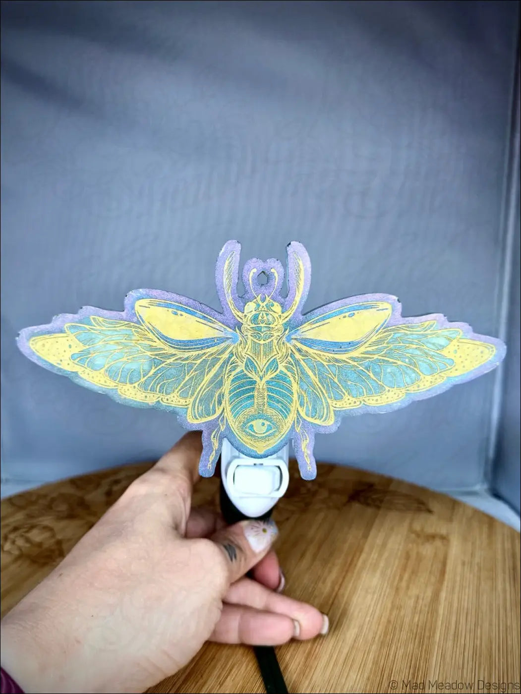 A stunning iridescent scarab resin night light with mesmerizing pastel purple base and aqua blue hues on plug-in base
