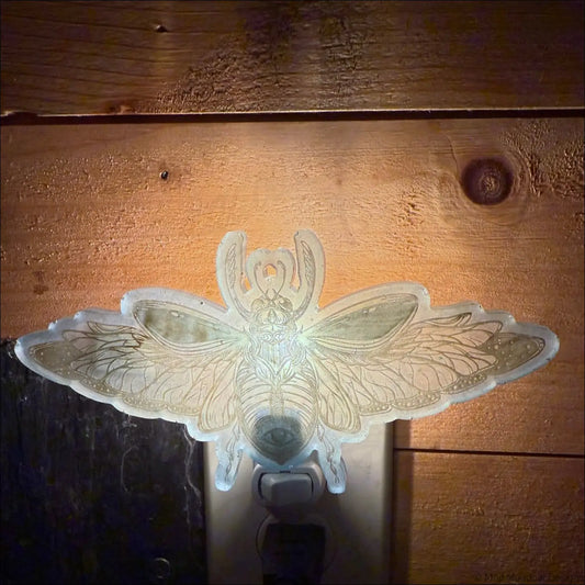 A translucent resin wall night light shaped like a stunning iridescent scarab with pastel purple and aqua blue hues