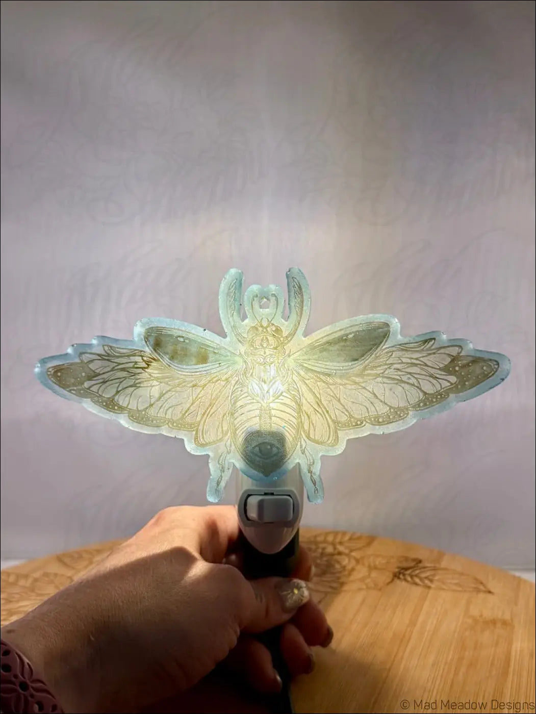 Stunning iridescent scarab resin wall night light with aqua blue hues and golden wing patterns glowing on plug-in base