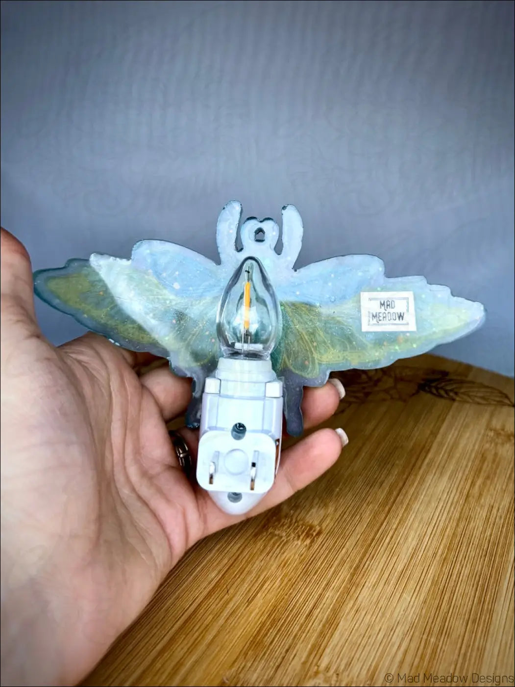 Translucent light blue and green resin nightlight shaped like a stunning iridescent scarab butterfly with delicate wings on plug-in base