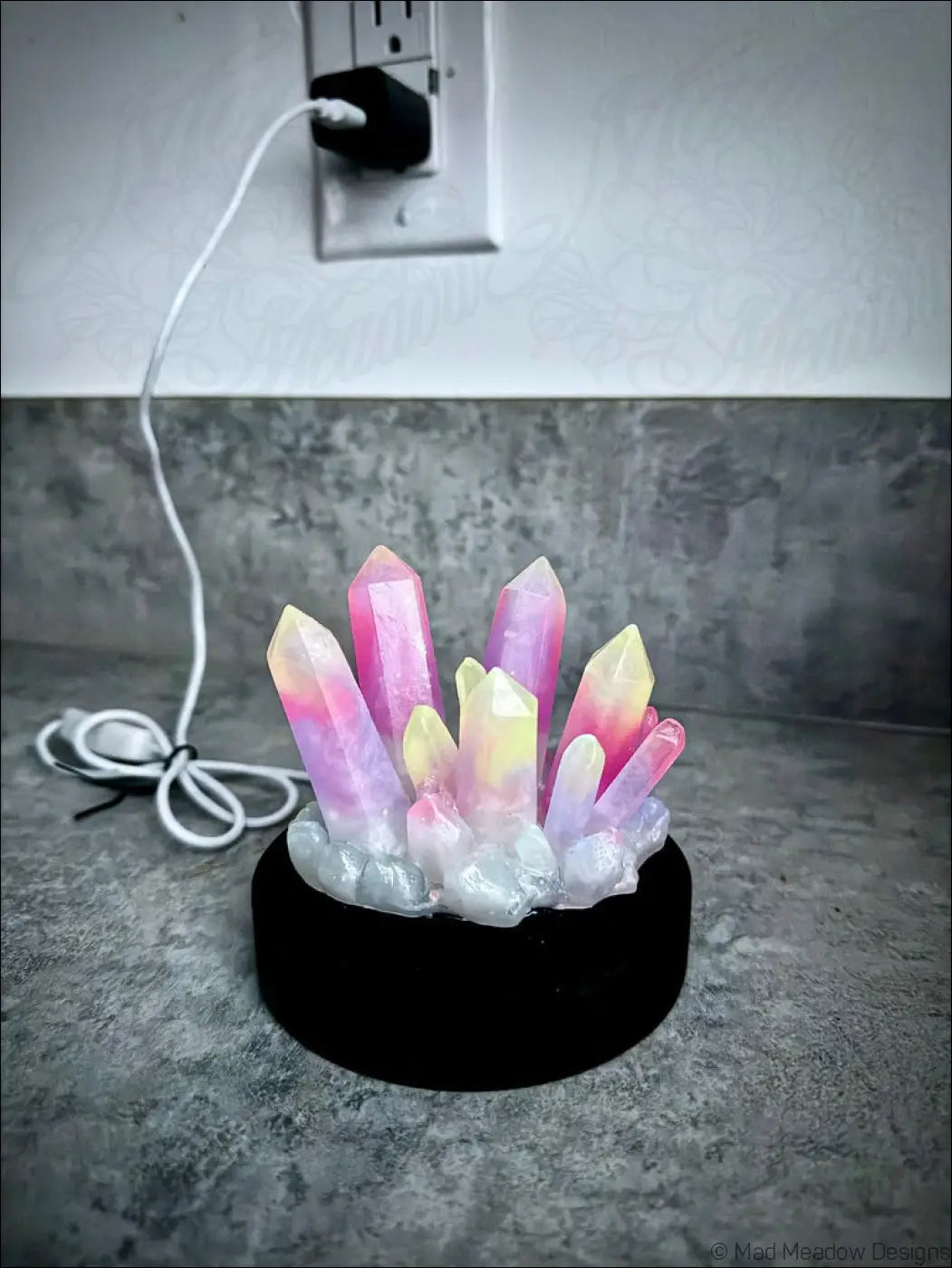 Large resin crystal cluster glow in the dark lamp with pink and yellow resin crystals on a black wooden base