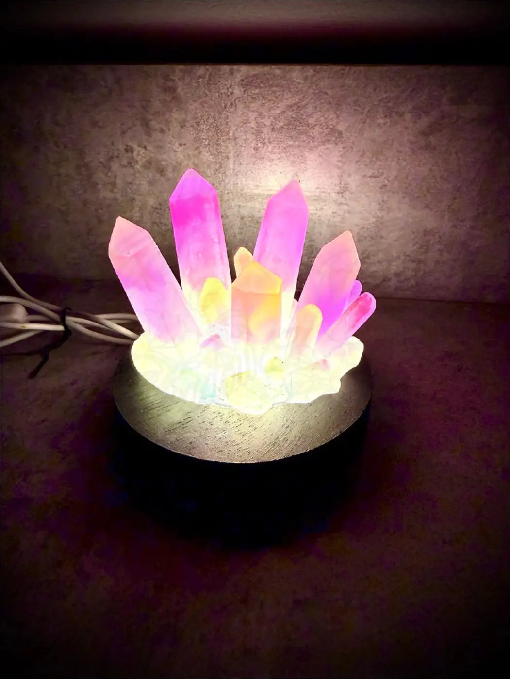 A large resin crystal cluster glow in the dark with vibrant pink and yellow quartz on a wooden base
