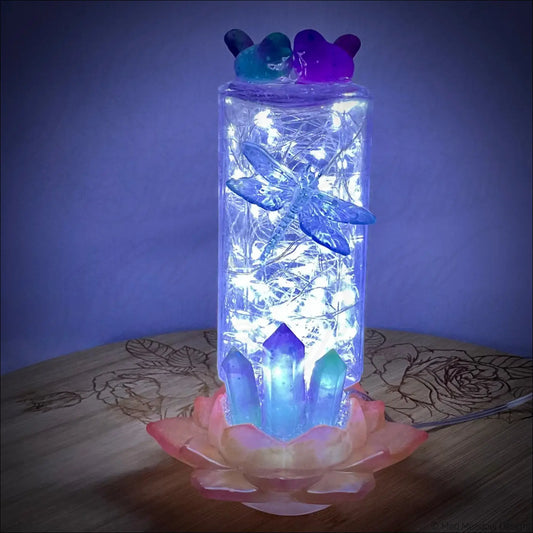 A glowing usb light with a translucent blue dragonfly and resin bears on an antique amethyst glass apothecary bottle