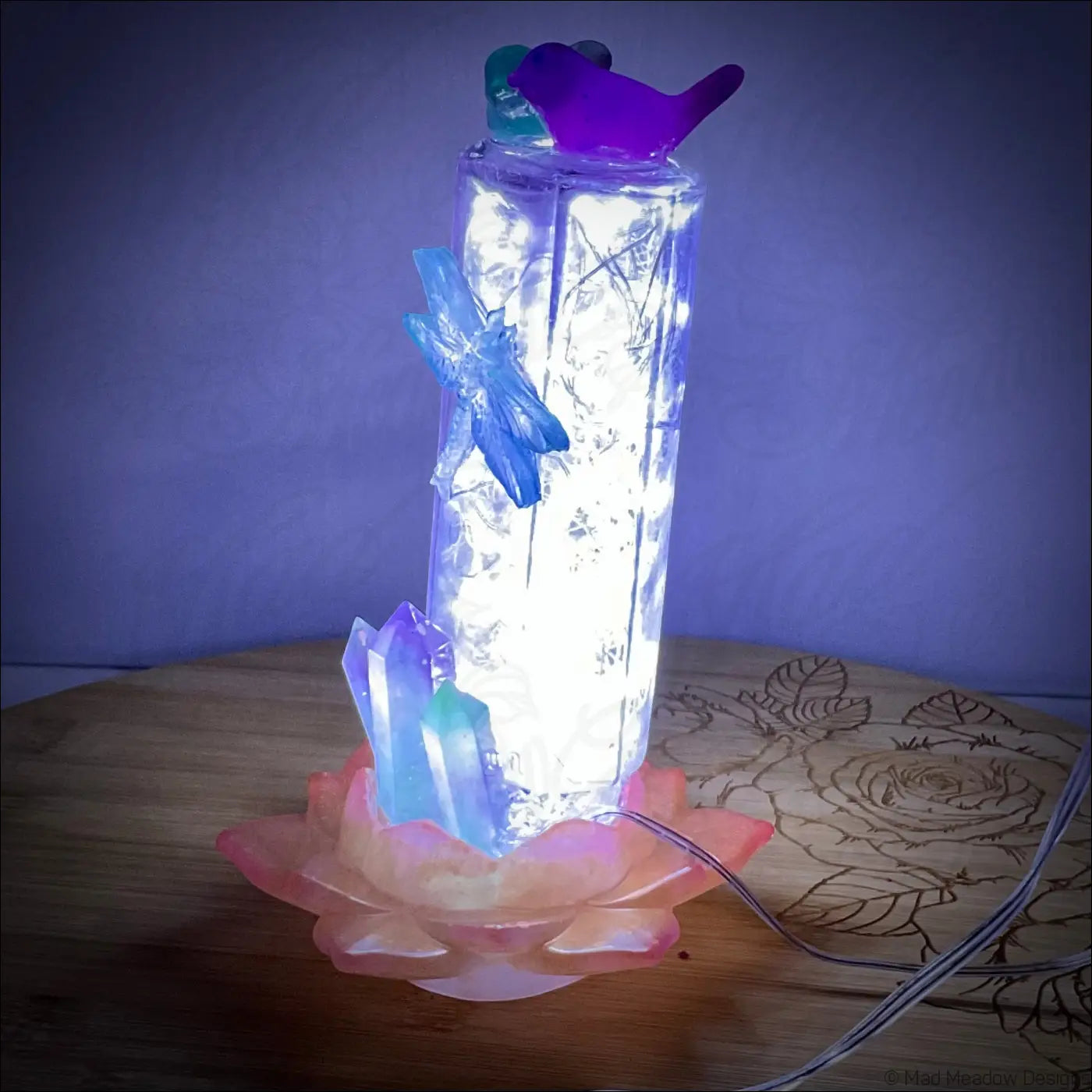 A glowing antique amethyst glass apothecary bottle usb light with fairy lights and butterfly accents on pink lotus base