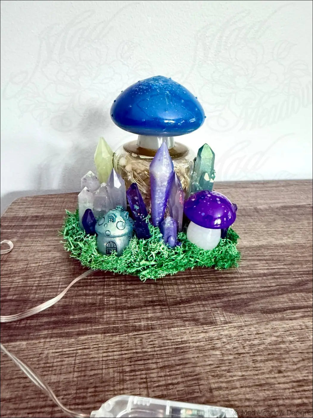 Vibrant blue and purple usb light shaped like a mushroom with crystal accents on a green moss base
