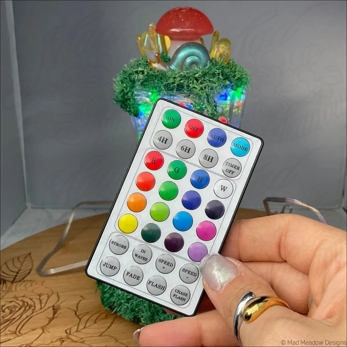 A sleek usb light remote control with white faceplate black border and colorful buttons for magical forest mushroom village light