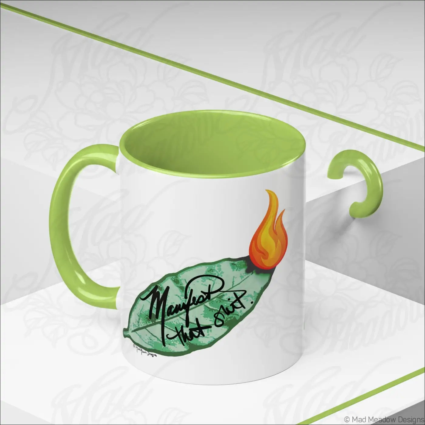 A white ceramic coffee mug with glossy finish lime green colored interior and burning bay leaf design manifest that slut text