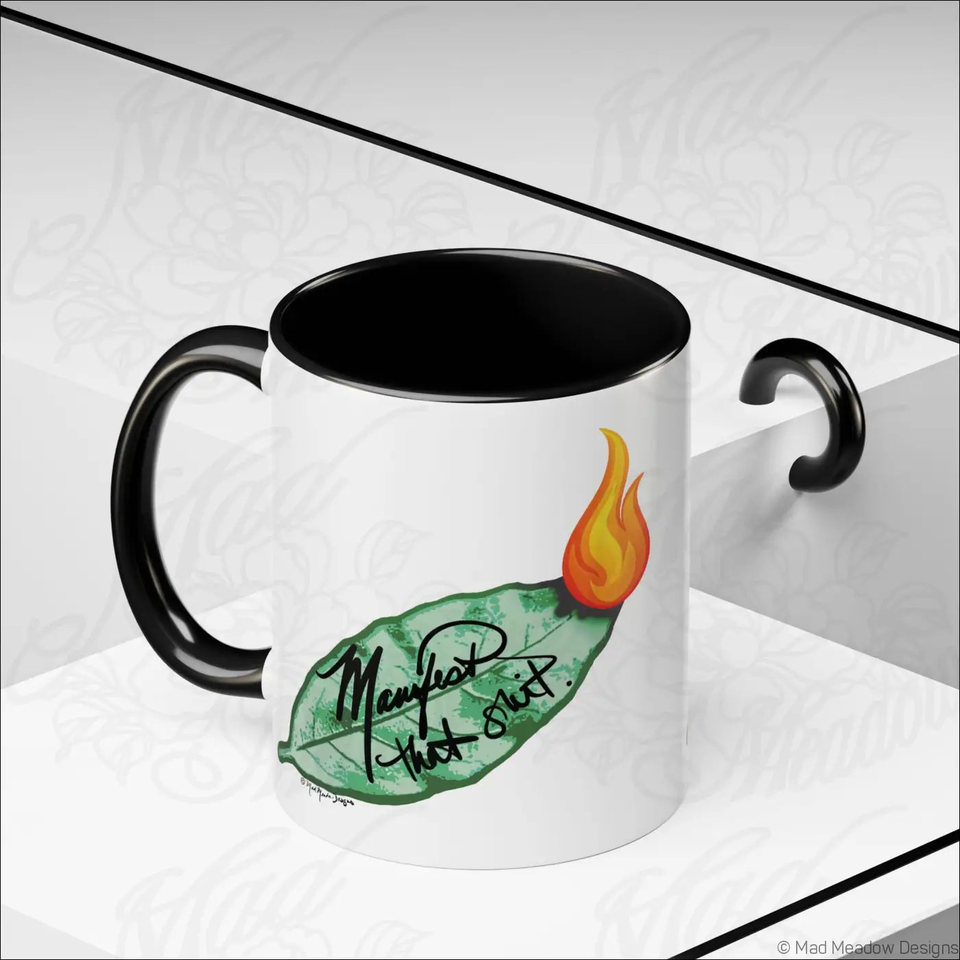 White ceramic coffee mug with glossy finish black interior handle and burning bay leaf design manifest that shit text