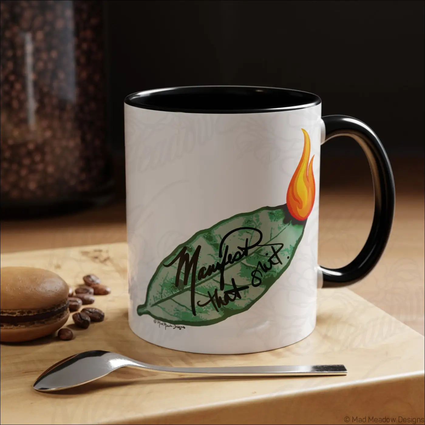 White ceramic mug with black rim and handle featuring a green bay leaf and orange flame design with glossy finish