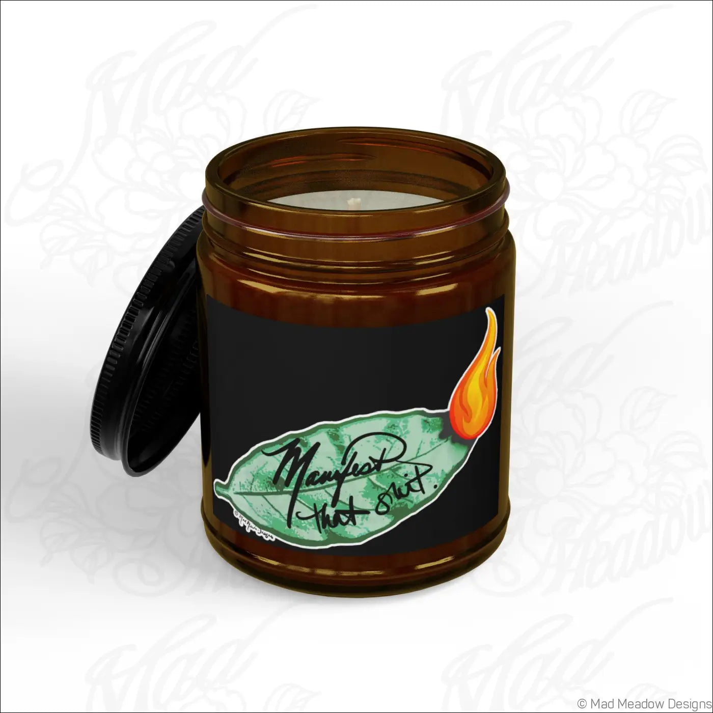 Brown glass jar soy wax candle with black lid and manifest that shit label burning bay leaf scent