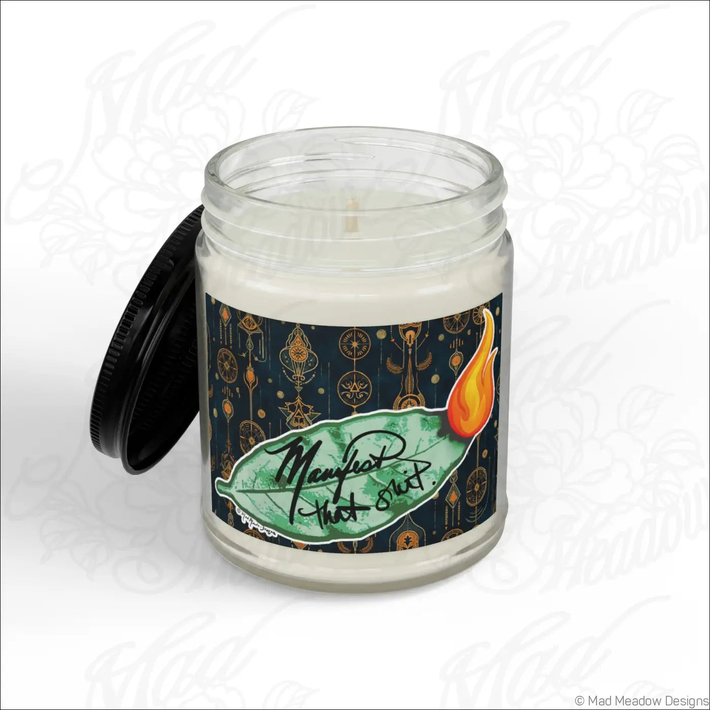 A white soy wax candle in a clear glass jar with a black lid and ornate label on a dark background