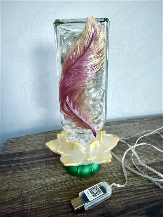 A translucent antique glass lamp with maroon and gold feather design on a golden lotus flower base usb light