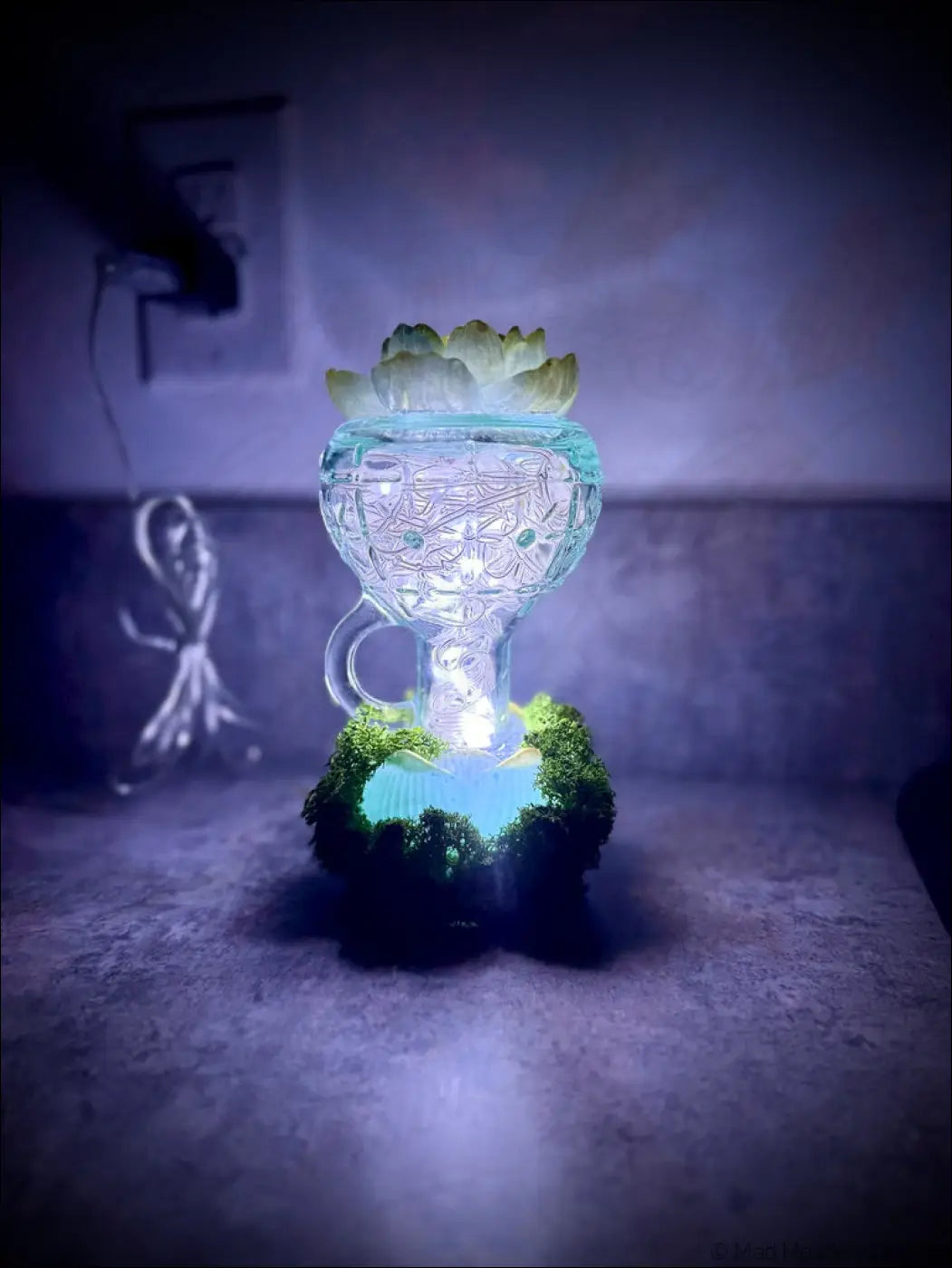 Mint green vintage glass bottle lamp with lotus flowers, moss, white lights, and a glowing blue etched glass hookah topped with succulent