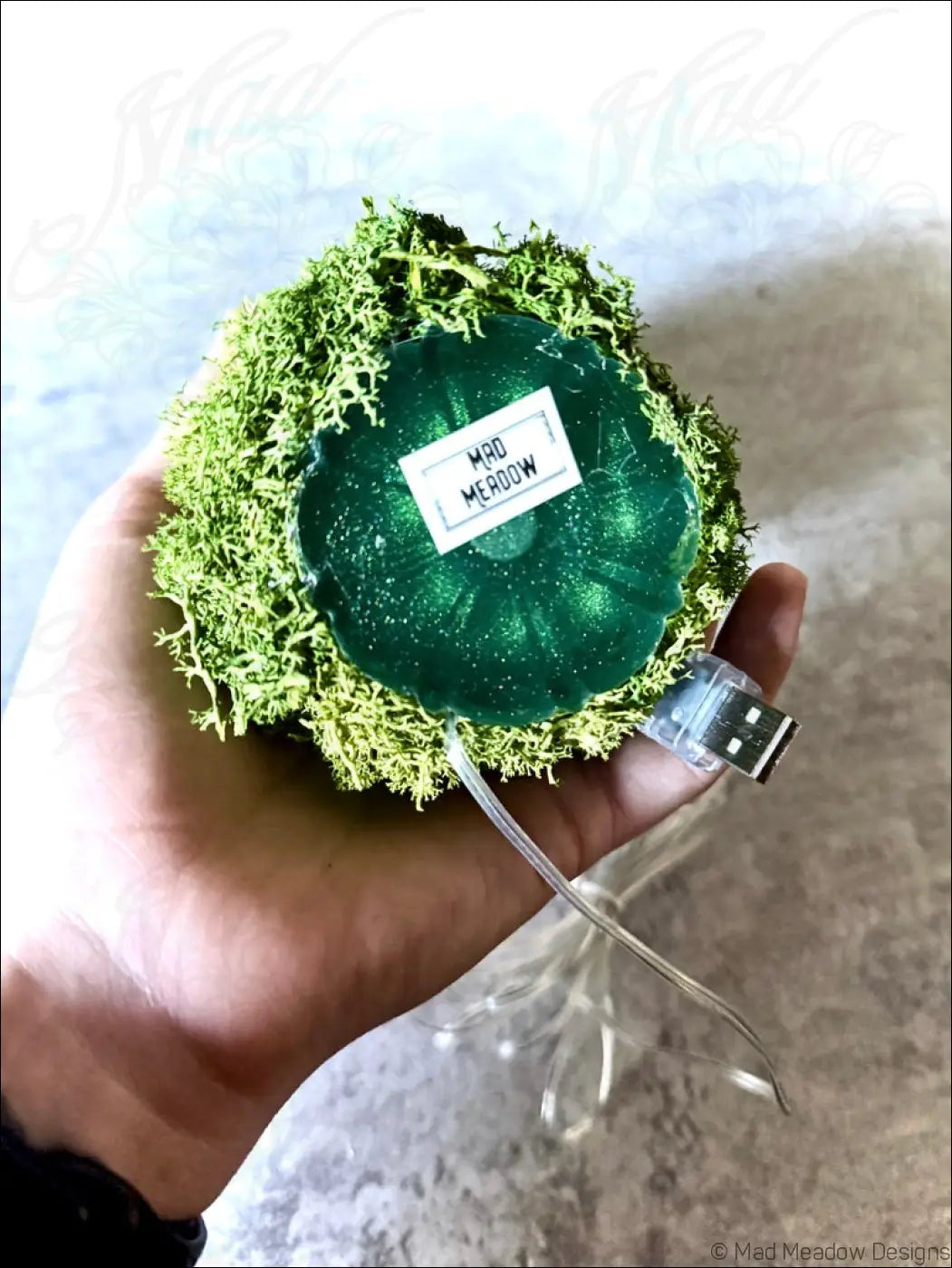 A mint green usb-powered lamp with gold lotus design, vintage glass bottle, moss, and white lights inside