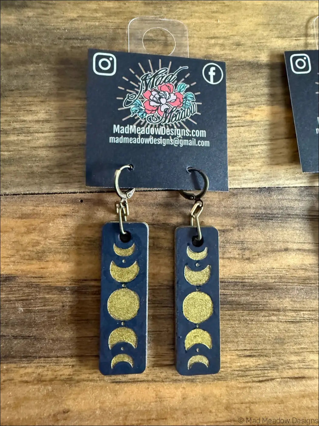 Dark blue rectangular wooden earrings with gold glitter moon phases design showcasing celestial magic style
