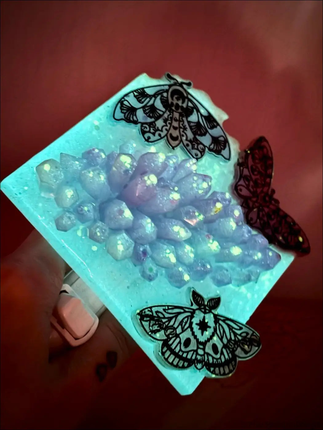 A square light blue resin coaster with mesmerizing crystal cluster and delicate iridescent moths decals in black line art
