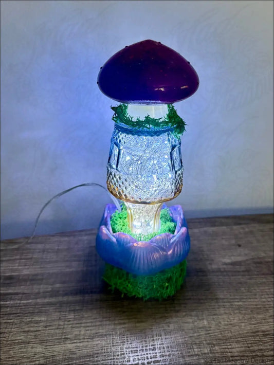 A glowing mushroom flower and moss glass bud vase with a purple cap and blue lotus base usb light