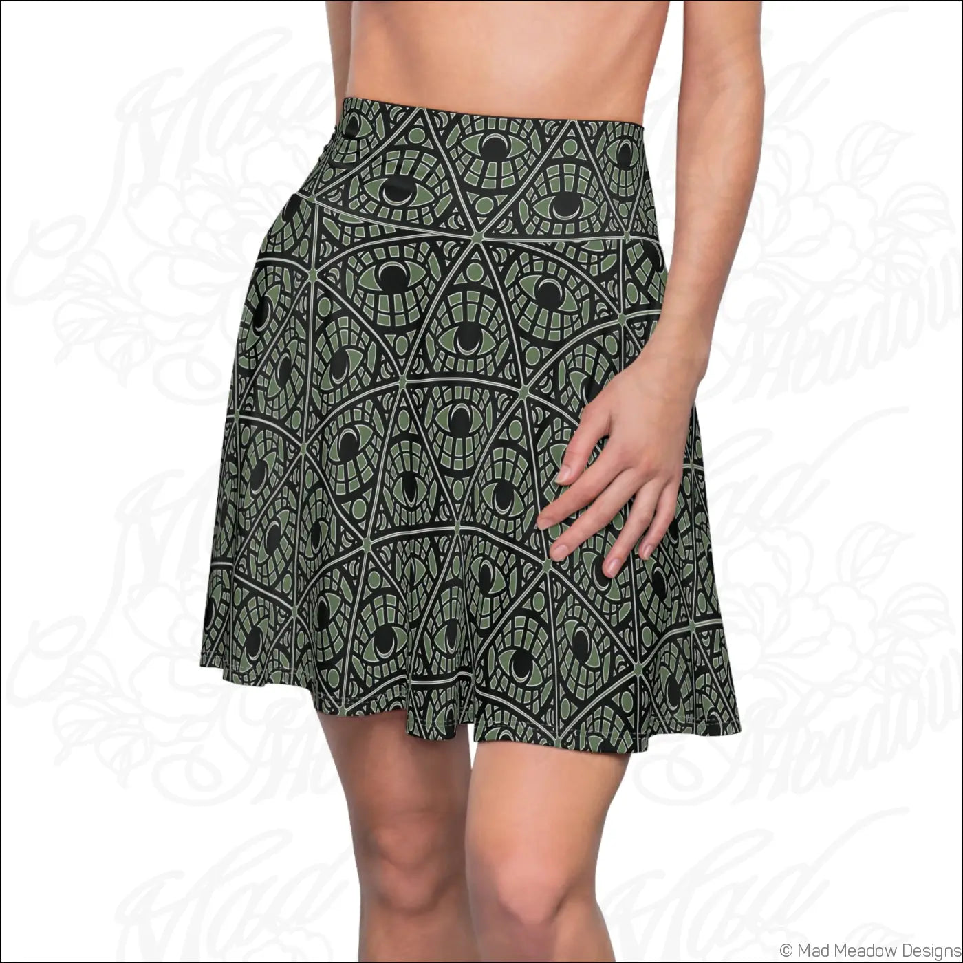 A sage skater skirt with a mystic eye tribal pattern in black and olive green stretch fabric and printed care label