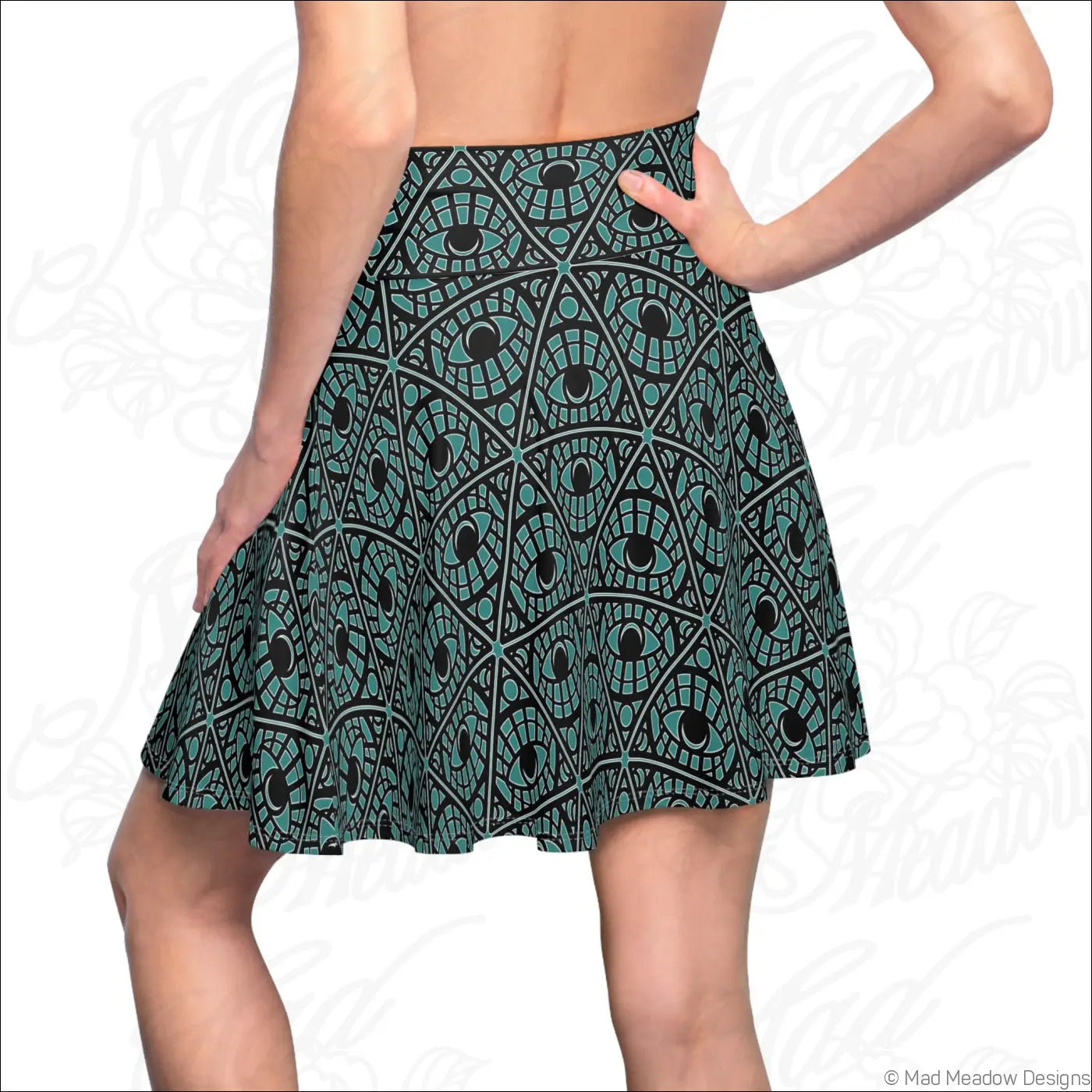 A flared teal skater skirt with a mystic eye tribal pattern on stretch fabric featuring a printed care label