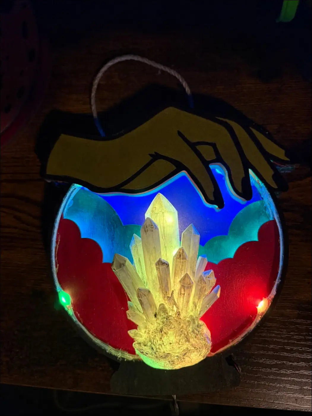 A glowing hand-painted hanging crystal ball with a yellow-gold hand and citrine hanging crystal cluster inside