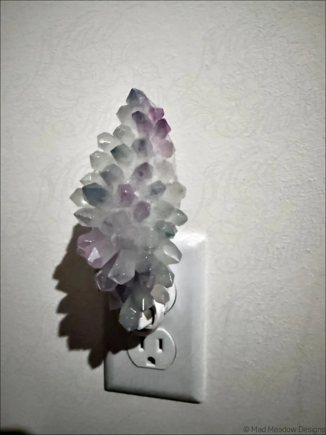 A pastel translucent white and purple crystal cluster resin wall night light plugged in for soft feather wall night glow