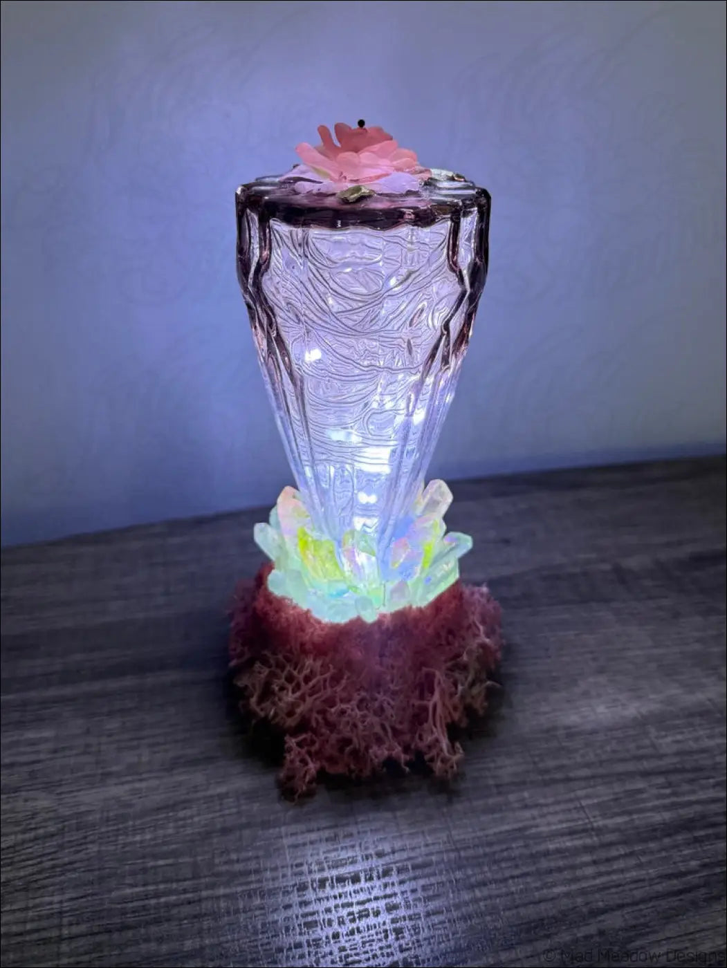 A translucent glass usb light with quartz crystal points glowing inside and a decorative pink flower on top