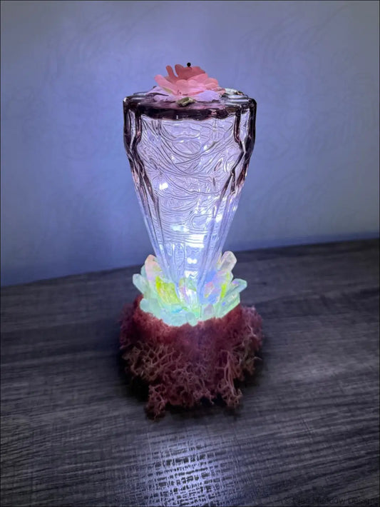 A translucent glass usb light with quartz crystal points glowing inside and a decorative pink flower on top