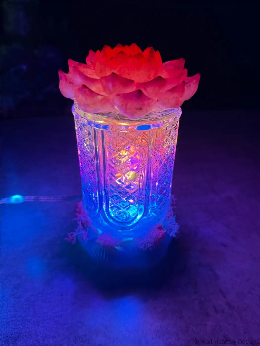 A glowing glass bud vase candle holder with a vibrant red lotus flower in pink fuchsia purple resin colors
