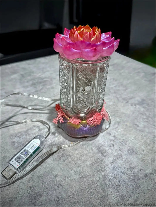 A translucent glass lotus flower lamp with a vibrant pink and orange top and etched patterns perfect as a bud vase light