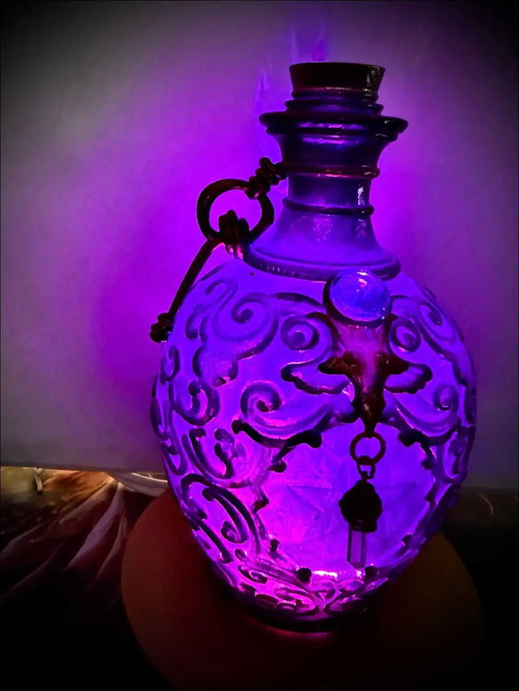 A translucent purple glass potion bottle light with intricate swirling etchings and a dark metal handle glowing softly