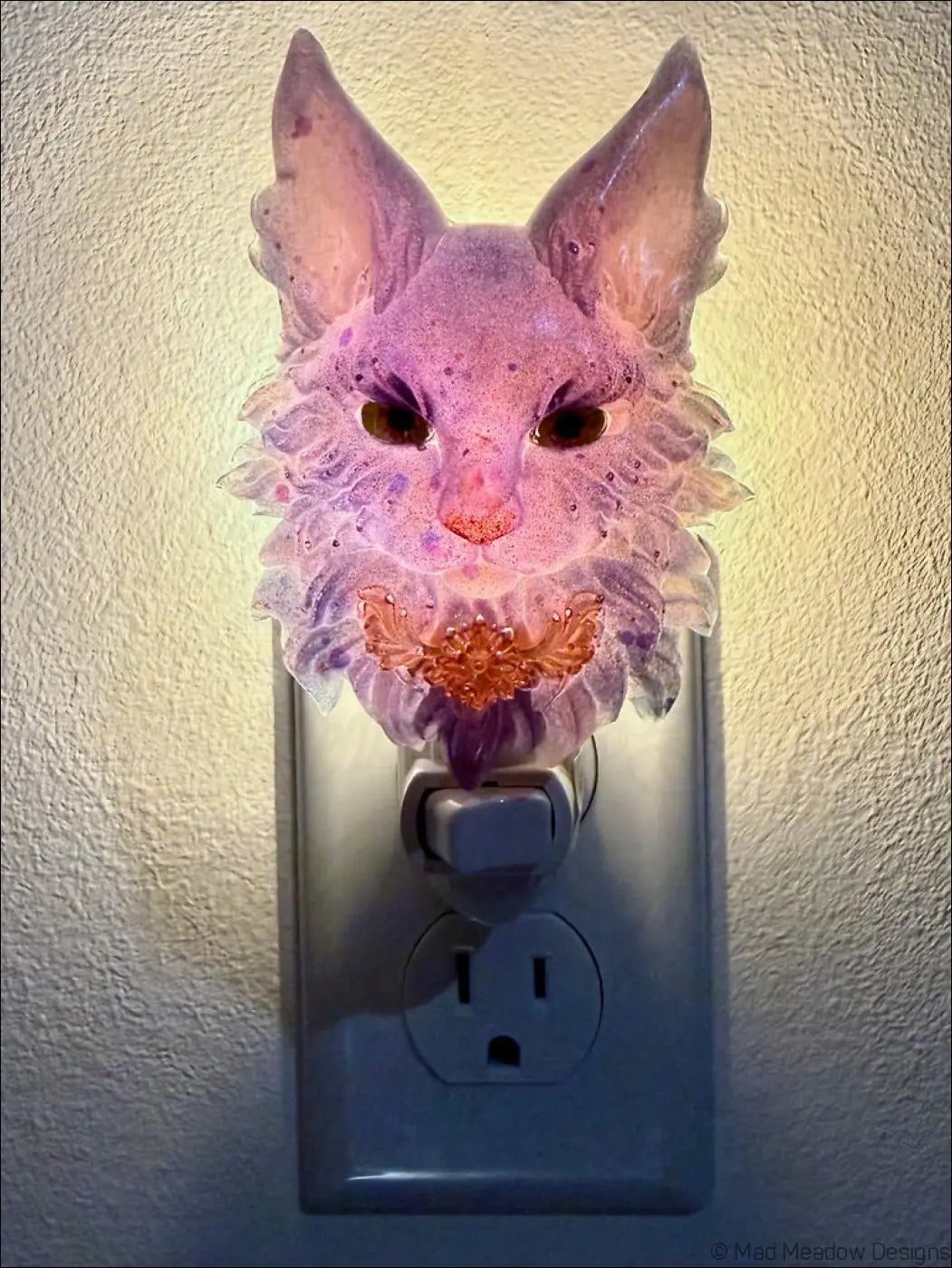Purple maine coon resin night light with warm white led glowing orange floral design plugged into outlet to bring whimsical charm